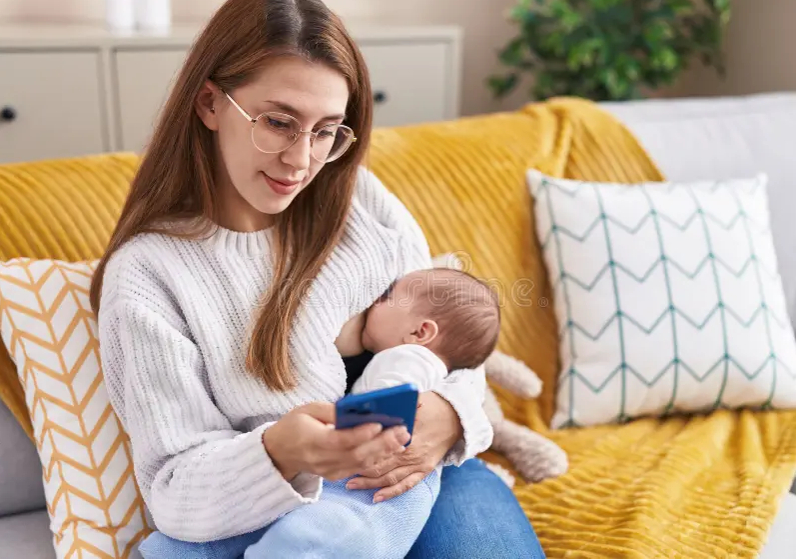 Moving to Motherhood phone Moving to Motherhood - woman reading text message on phone while nursing baby